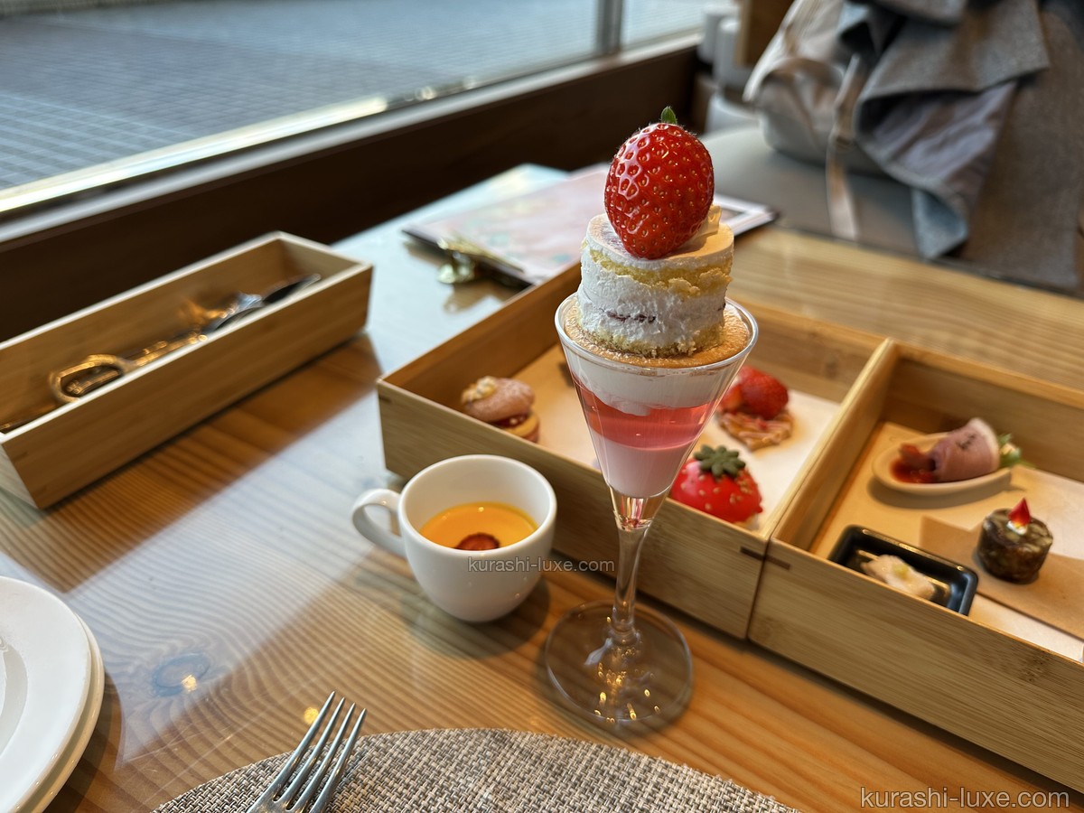 ヒルトン東京ベイのアフタヌーンティー。グラスに盛られたデザートと、木箱に入った軽食が並ぶ窓際の席